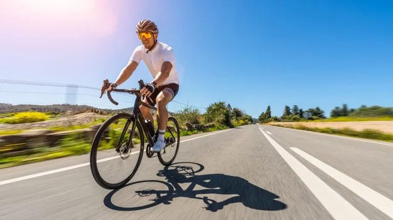 Uomo Adulto su una bicicletta da corsa che sale la collina al mare mediterraneo paesaggio strada costiera su mallorca isola balearica. movimento sfocatura colpo