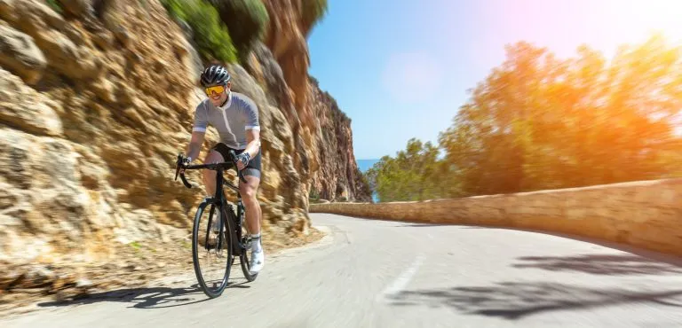 Mann Erwachsene auf einem Rennrad Klettern den Hügel am Mittelmeer Landschaft Küstenstraße auf Mallorca balearischen Insel
